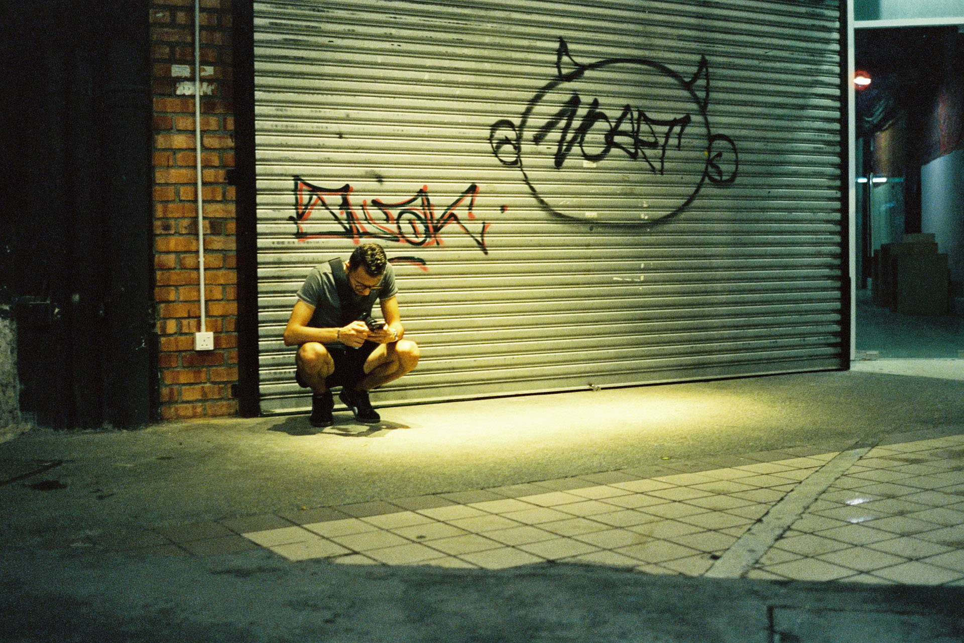 CineStill 800T - A man squatting under yellow lighting